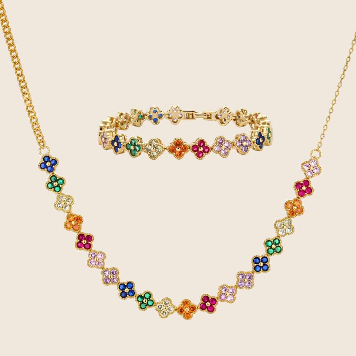 Colorful four-leaf clover jewelry set with rainbow cubic zirconia stones in gold-plated setting on white background
