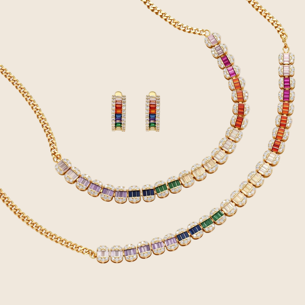 Gold-plated jewelry set featuring rainbow baguette-cut cubic zirconia stones in geometric design on cream background