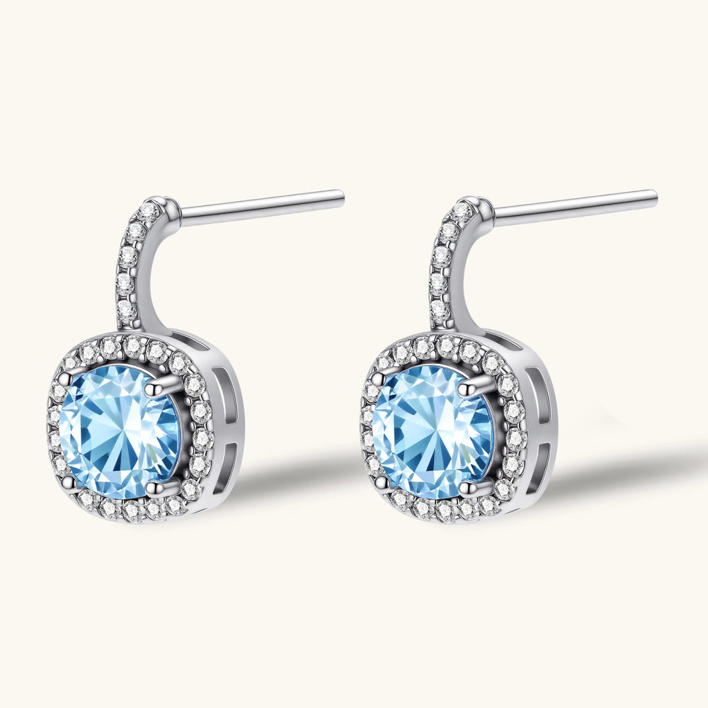 Sterling silver drop earrings featuring cushion-cut blue moissanite stones surrounded by sparkling halo settings