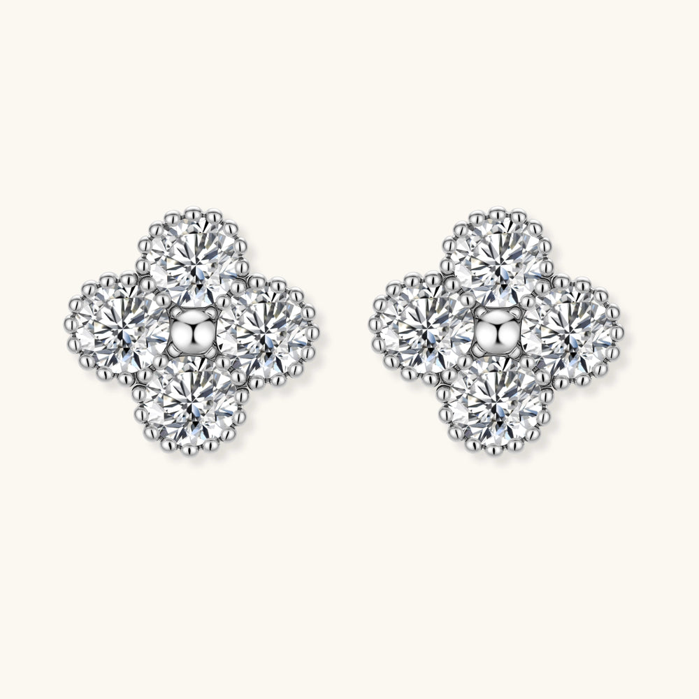 Dainty sterling silver quatrefoil stud earrings with four brilliant moissanite stones and center accent on white background.