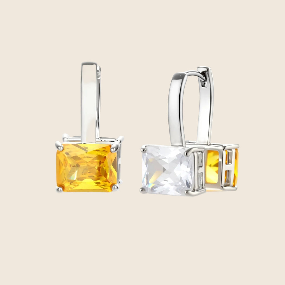 Silver curb-chain necklace and hoop drop earrings set with paired yellow and clear square zirconia stones.