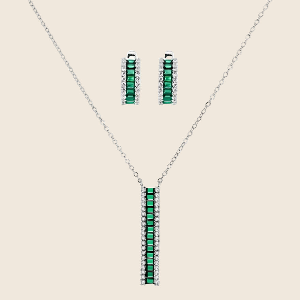 White gold plated jewelry set with emerald green rectangular stones and clear crystals in geometric rows on white background.