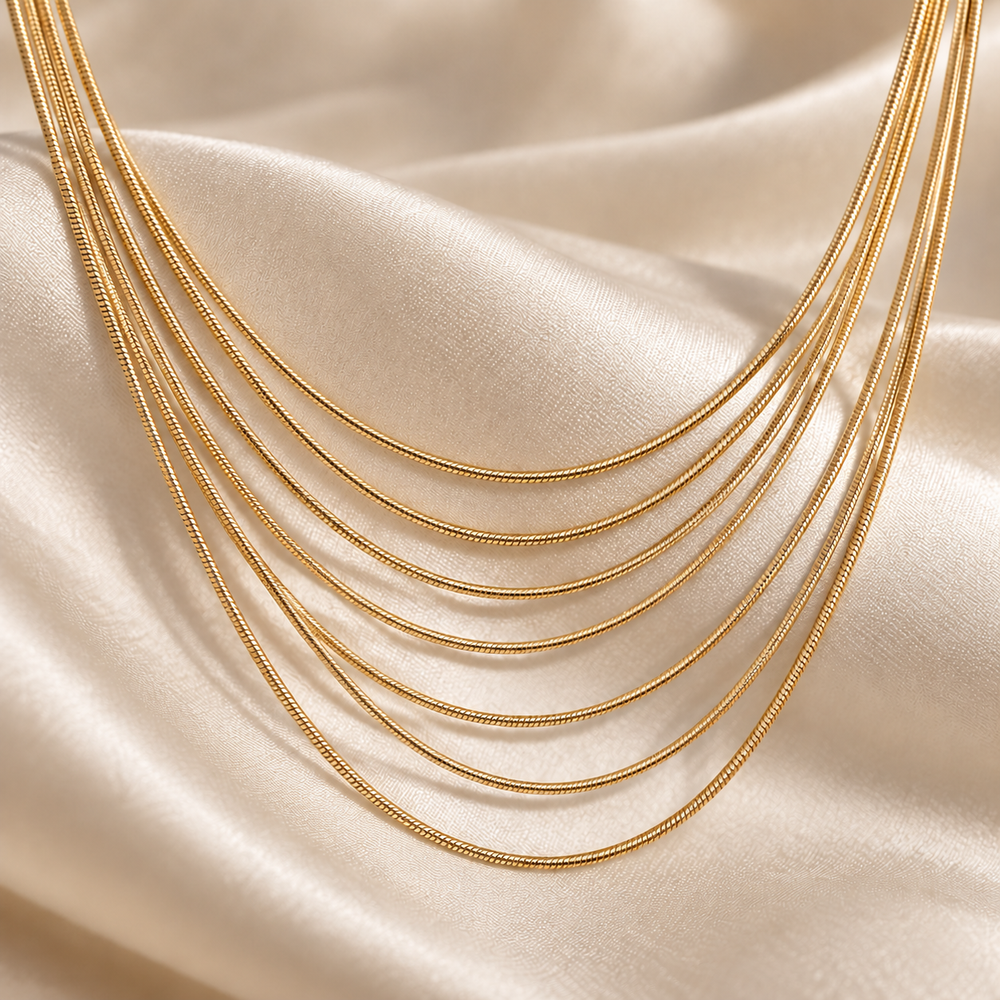 Close-up of the seven graduated gold-tone chains of the Golden Hour Layers Necklace on ivory silk.